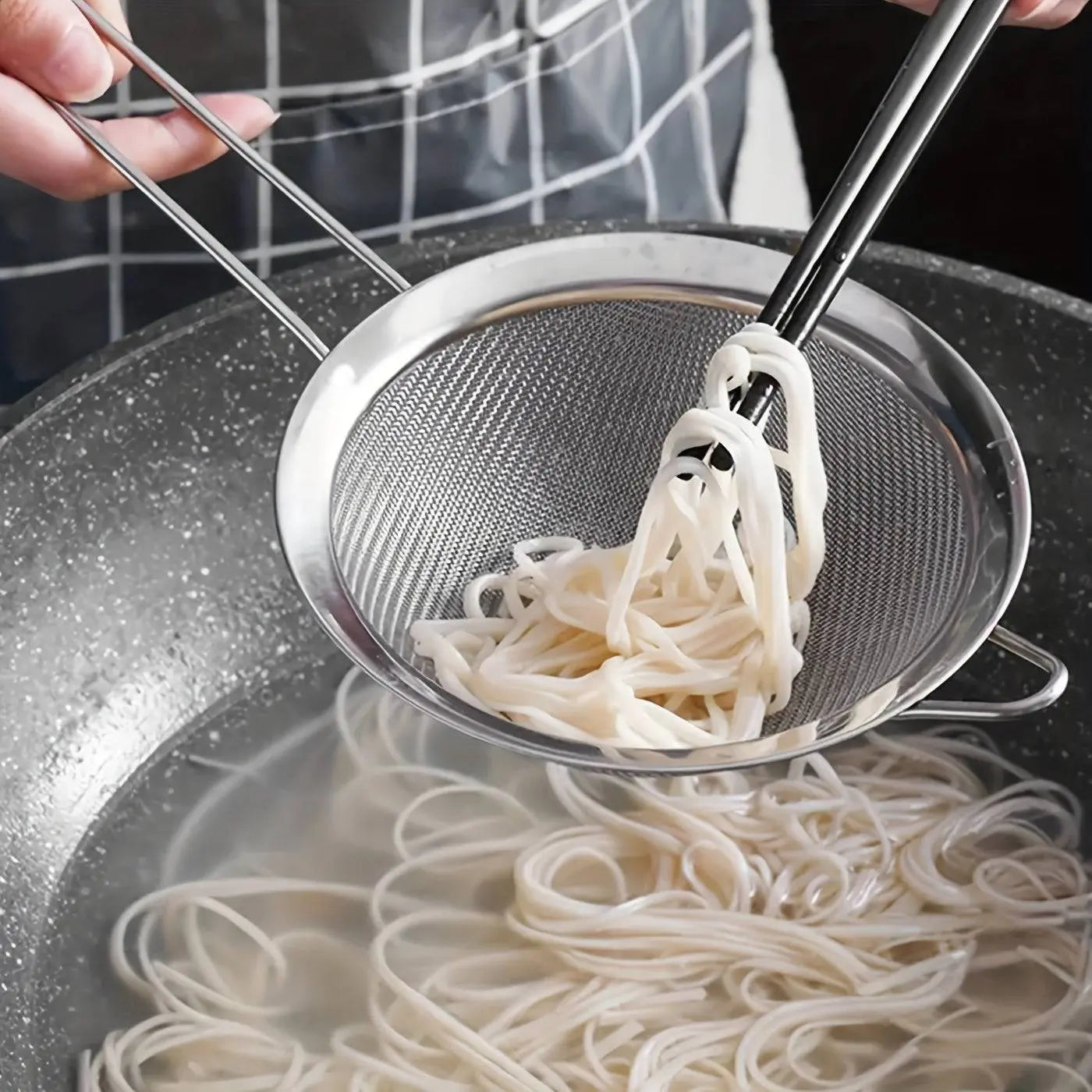 Fine mesh Stainless Steel Strainer Set used to lift noodles from boiling water, durable and essential for kitchen straining needs.