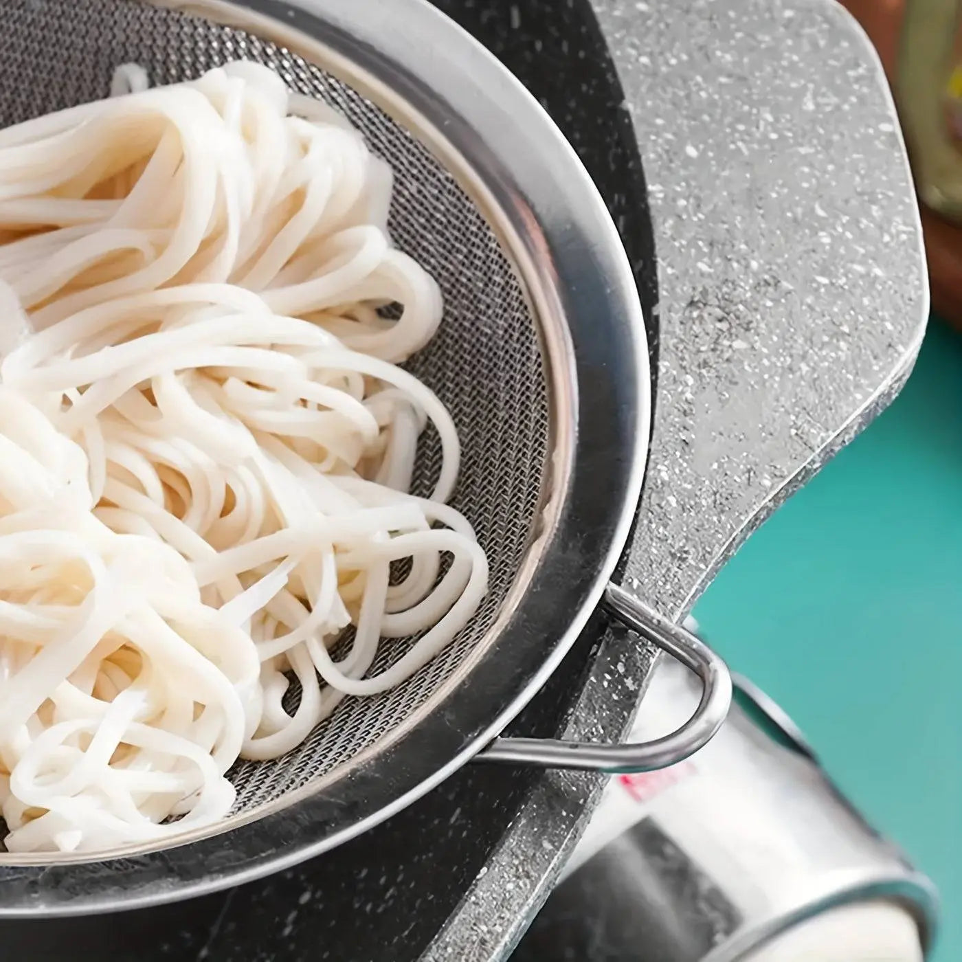 Stainless Steel Strainer draining cooked noodles, highlighting the fine mesh design perfect for kitchen use in straining pasta and vegetables.