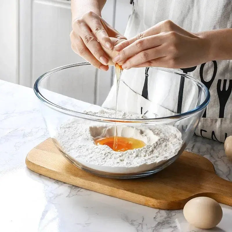 Large Glass Salad Bowl - Durable & Versatile Kitchen Essential used for mixing flour and cracking an egg on a wooden board.