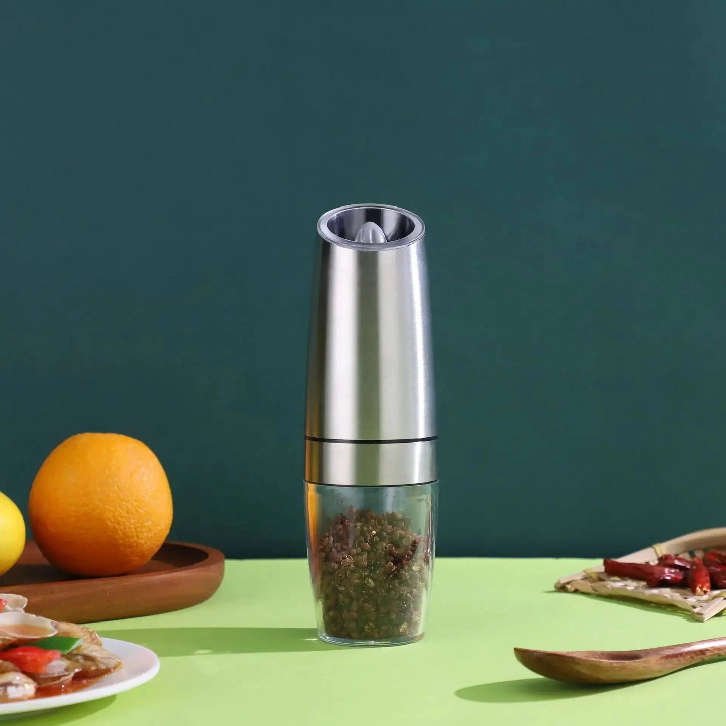 Single stainless steel Automatic Pepper Grinder - Electric Grinder on a green table, designed for easy one-touch spice grinding and sleek style.
