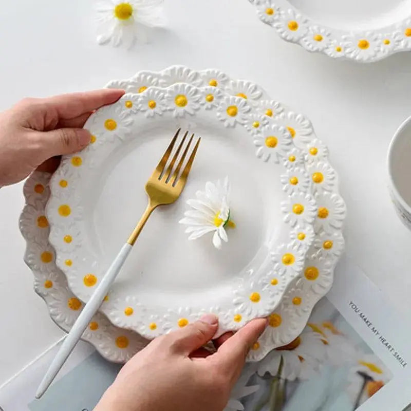 Hand holding a plate from the Ceramic Embossed Little Daisy Plate Dinner Set, emphasizing the delicate daisy detailing and elegant craftsmanship.