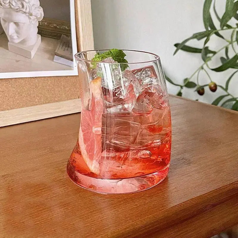 Transparent Graceful Glass Cup with curved silhouette, filled with iced grapefruit drink, microwave and dishwasher safe, ideal for stylish beverages.