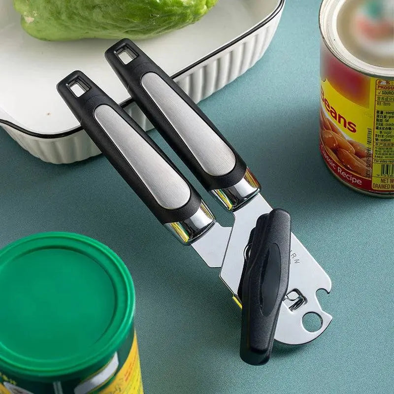 Professional Tin Manual Can Opener - Manual Can Opener | Ergonomic, Durable, Multifunctional placed on a kitchen counter with canned goods and vegetables.