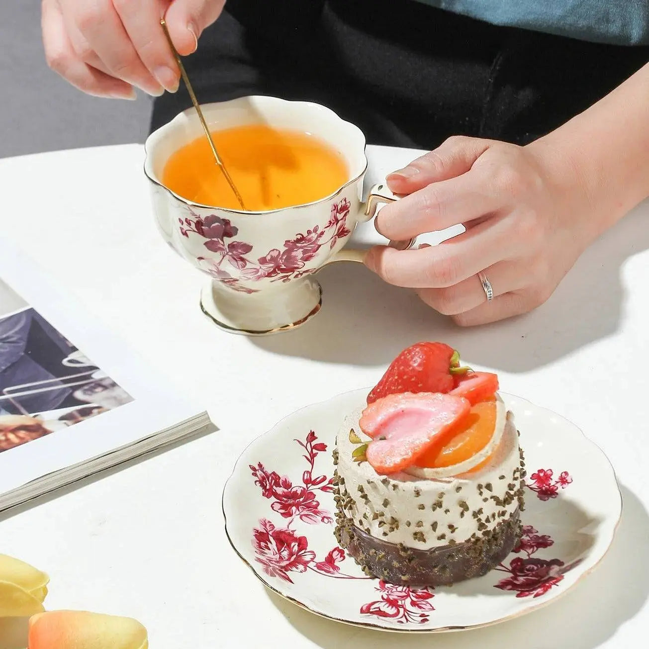 Red Flower Ceramic Coffee Set showing a hand stirring tea in a floral cup, microwave safe, ideal for personal or gift use.