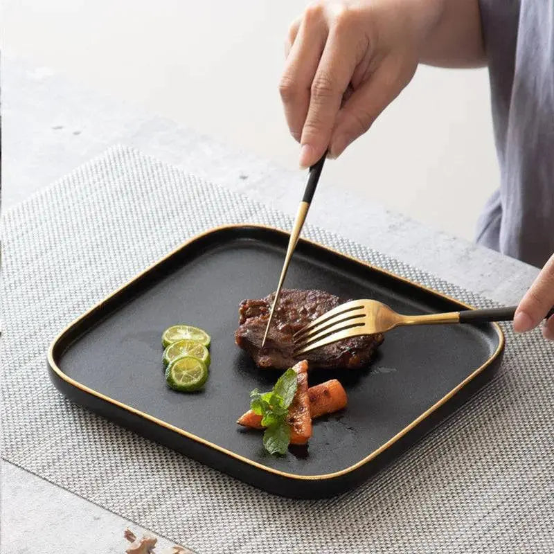 3 Size Black Dishes Set - Modern Dining Essentials displayed with a person cutting steak on a matte black plate, highlighting its elegant gold-trimmed design.