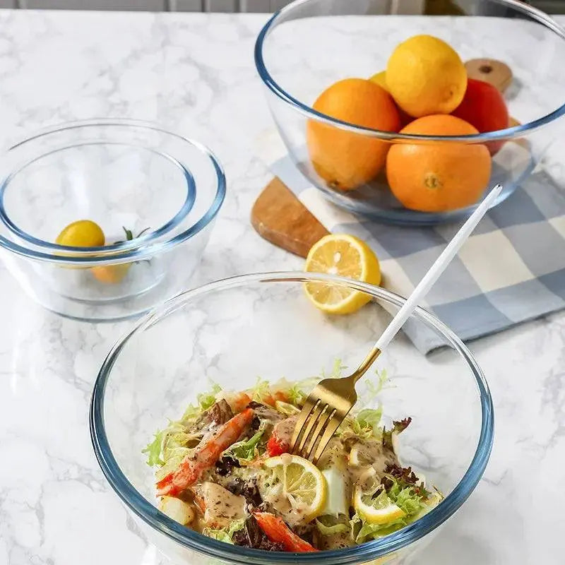 Glass Salad Bowl - Durable & Versatile Kitchen Essential filled with fresh salad, fruits, and lemons on a marble countertop.
