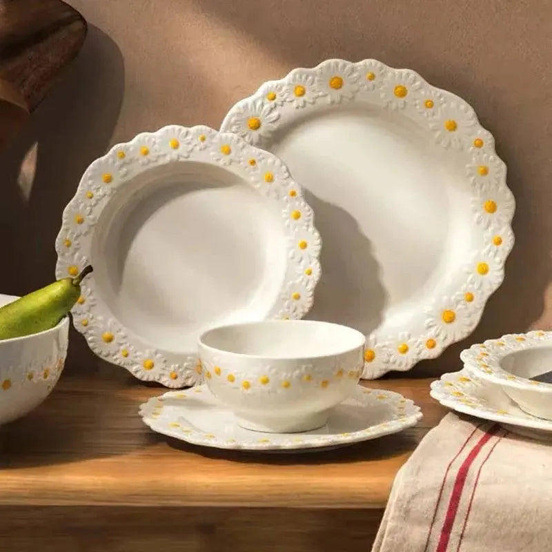 Full Ceramic Embossed Little Daisy Plate Dinner Set displayed on a wooden surface, showcasing plates and bowls with charming daisy patterns.