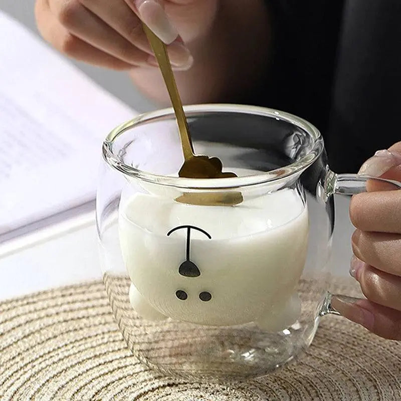 Borosilicate Glass Cup - Elevate Sipping | Spill-Resistant being stirred with a golden spoon, highlighting its creative bear design and premium quality.