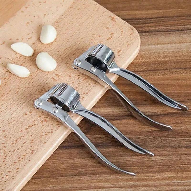 Two Stainless Steel Garlic Mashers - Manual Garlic Crushers on a wooden board with garlic cloves, durable and efficient kitchen tools.