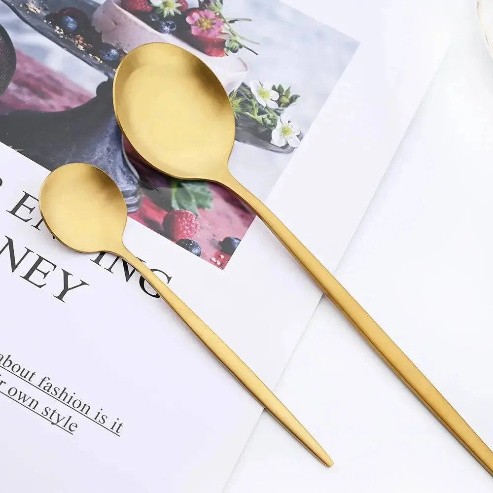Close-up of 16 Pieces Dinnerware Set highlighting matte gold spoons on a magazine, emphasizing elegant craftsmanship and design.