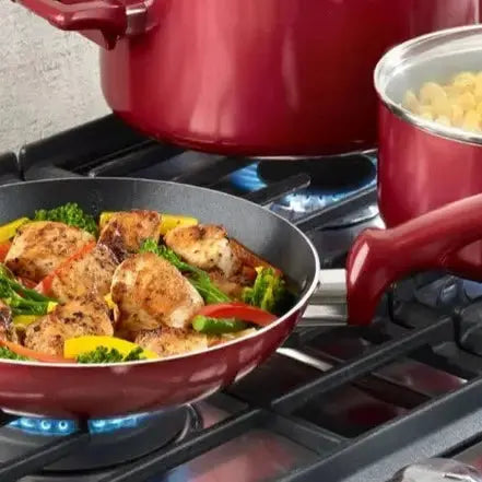Easy Care Cookware Set - 12 Piece Non-Stick | Durable red non-stick frying pan cooking chicken and vegetables on a gas stove, perfect for quick meals.