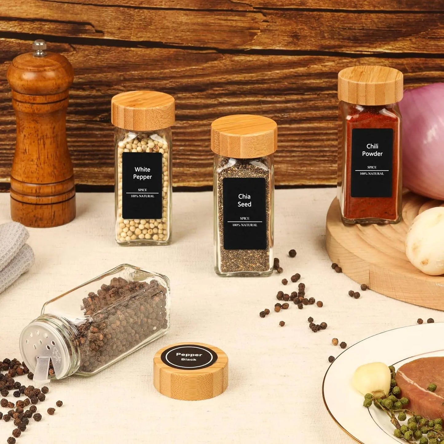 Glass Spice Jar Set with Bamboo Lids | Airtight, Clear Design featuring labeled jars of spices like white pepper, chia seed, and chili powder on a kitchen counter.