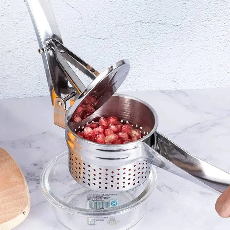 Stainless Steel Manual Juicer - Multifunctional | Compact Design pressing pomegranate seeds into a glass bowl, showcasing its multifunctionality.