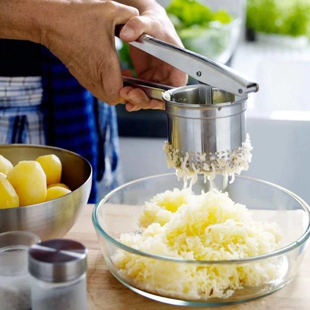 Stainless Steel Manual Juicer - Multifunctional | Compact Design used to mash boiled potatoes into a glass bowl, perfect for versatile kitchen use.