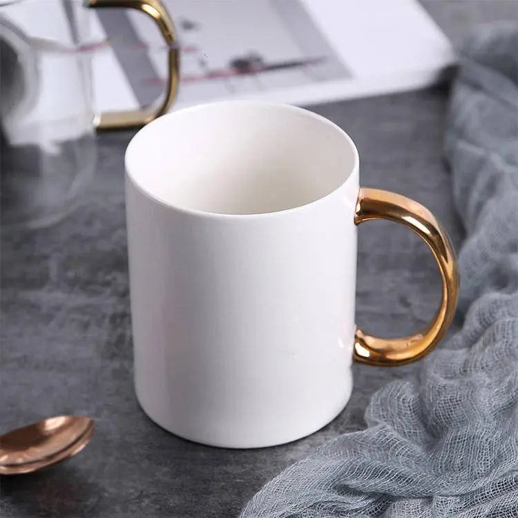 Elegant Coffee Cup with Gold Handle placed near a magazine and gold spoon, ideal for enhancing your coffee experience.