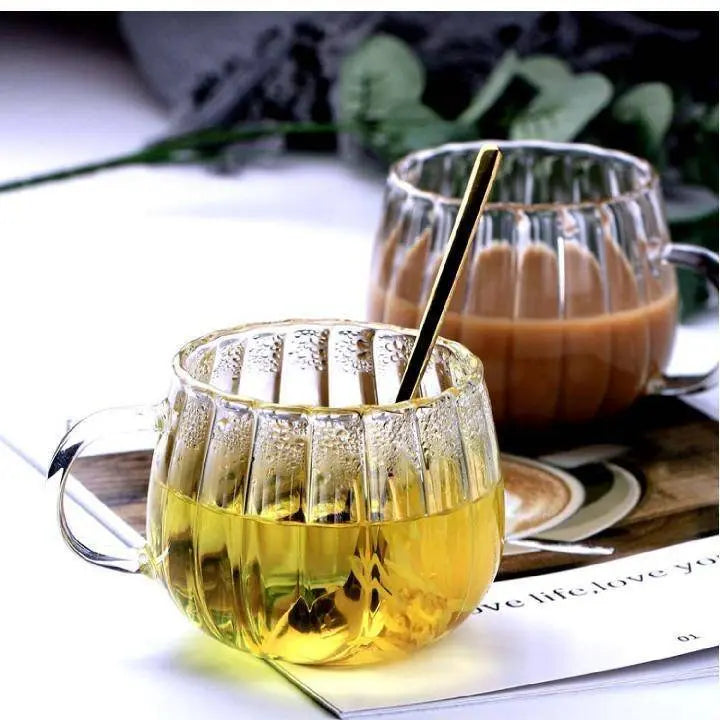 Heat-Resistant Striped Glass Mug with tea and coffee on a magazine background. Elegant heat resistant glass mug for hot and cold drinks.