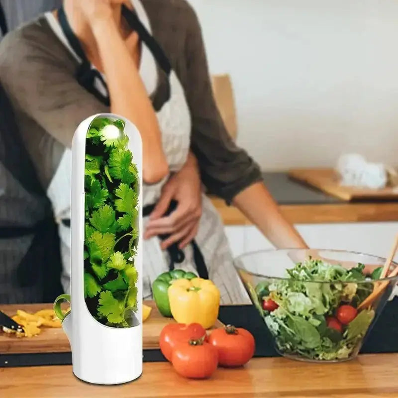 Herb Preserver Pod - Herb Freshness Container on a kitchen counter with a woman preparing salad, showcasing compact herb storage.