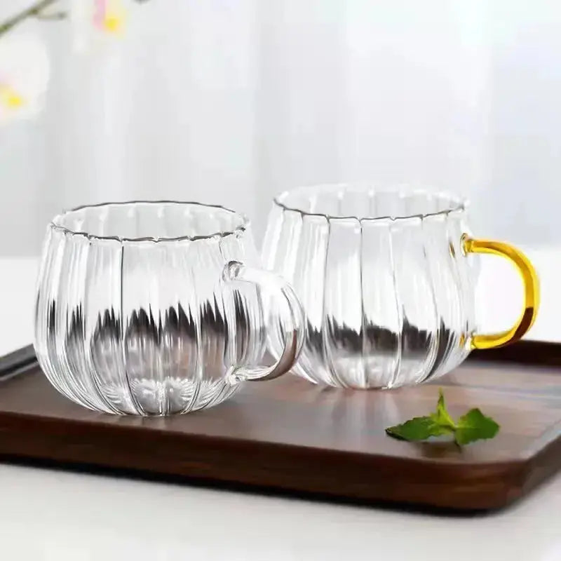 Two Heat-Resistant Striped Glass Mugs with clear and gold handles on a wooden tray. Premium heat resistant glass mugs for modern kitchens.