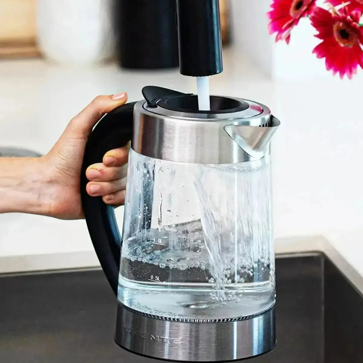 Electric Stainless Steel Kettle - Fast Boiling | Auto Shut-Off, glass kettle being filled with water under a faucet, sleek stainless steel design.