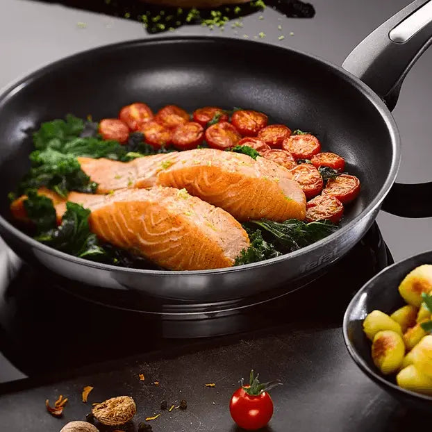 Easy Care Cookware Set - 12 Piece Non-Stick | Durable frying pan cooking salmon, spinach, and tomatoes, showcasing non-stick performance for easy meals.
