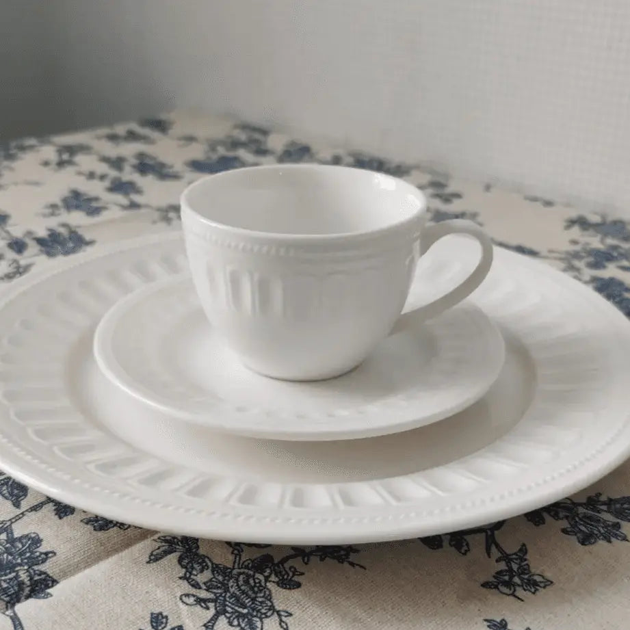 Charlotte Mug Set - Stylish & Durable Mugs | Microwave Safe, showcasing a white mug and matching plates with embossed detailing on a floral tablecloth.