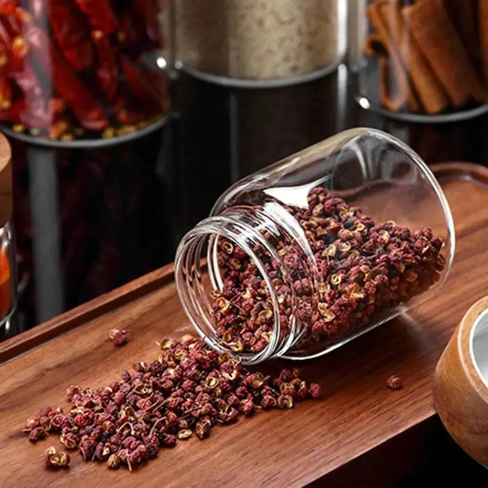 Glass Spice Jars with Wood Lids - Airtight Seal | Buy 2, Get 1 Free showing a jar tipped over with dried spices spilling onto a wooden tray.
