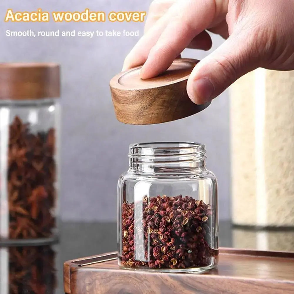 Glass Spice Jars with Wood Lids - Airtight Seal | Buy 2, Get 1 Free highlighting a hand lifting an acacia wood lid from a small spice jar filled with peppercorns.