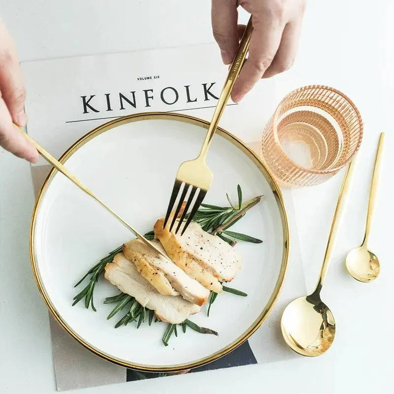 Golden fork and knife from the 24-piece cutlery set slicing chicken on a festive plate, enhancing holiday dining.