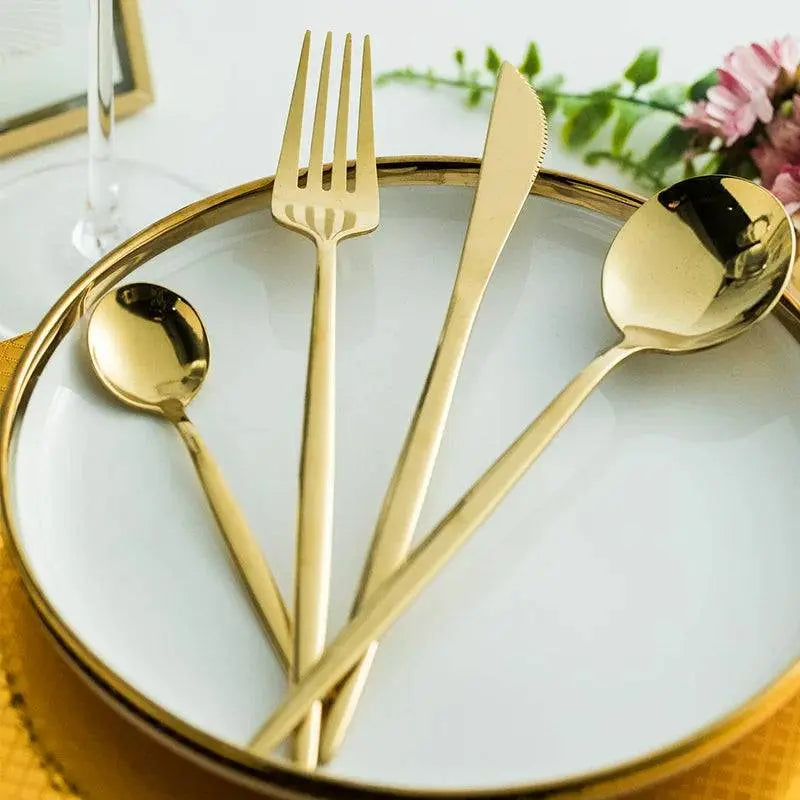 Elegant 24-piece golden cutlery set arranged on a white plate with gold rim, ideal for holiday dining decor.